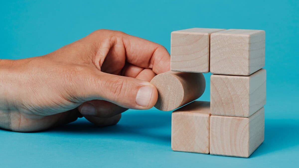 A hand placing a circle into a square structure to exemplify neurodiversity