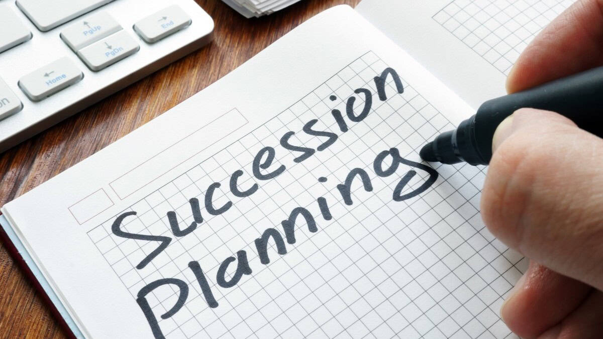 person writing the words, succession planning, on paper